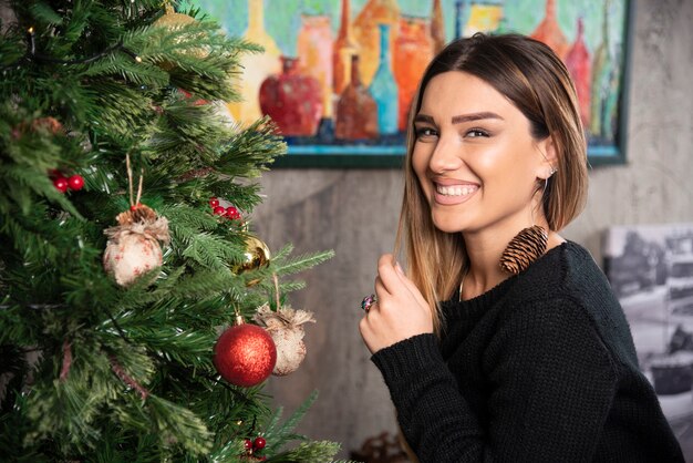 Uma mulher feliz sentada perto da bela árvore de Natal. Foto de alta qualidade