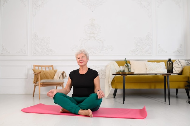 Uma mulher idosa faz ioga em casa o conceito de um estilo de vida saudável na velhice