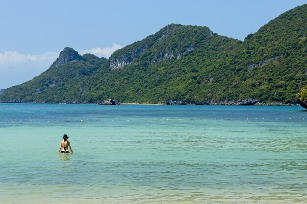 Uma mulher irreconhecível nadando no mar do Parque Nacional Marinho de Ang Thong.