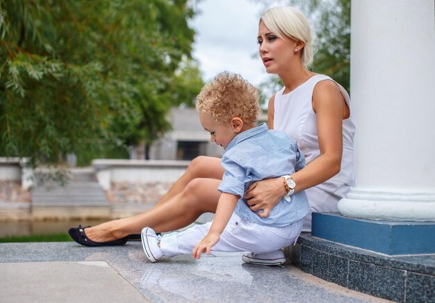 Uma mulher loira de vestido branco e seu filho pequeno bonito.