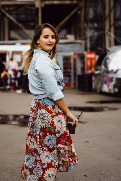 Uma mulher nova bonita com cabelo longo com um vidro do café é de sorriso e de riso.