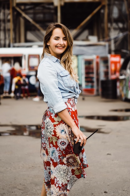 Uma mulher nova bonita com cabelo longo com um vidro do café é de sorriso e de riso.