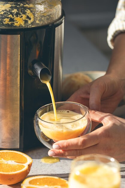 Uma mulher preparando suco de laranja fresco para o café da manhã na cozinha