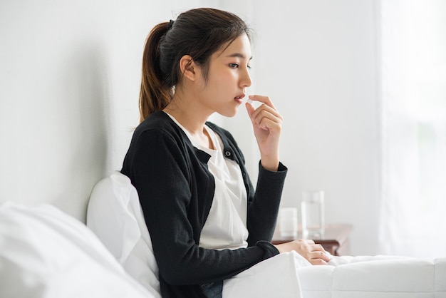 Uma mulher que não está bem no sofá e está prestes a tomar antibióticos.