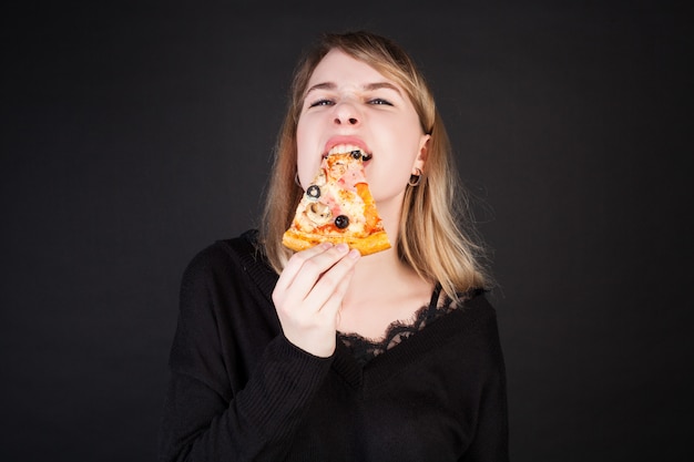 Uma mulher segura fatias de pizza, lançando-as como facas. foto do conceito para publicidade de pizza.