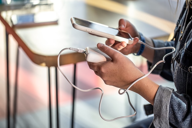 Uma mulher segura um banco de energia e um telefone nas mãos