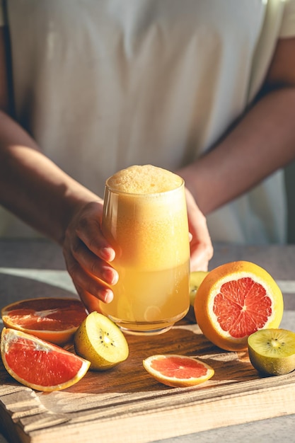 Foto grátis uma mulher segura um copo de suco recém-espremido em suas mãos na cozinha