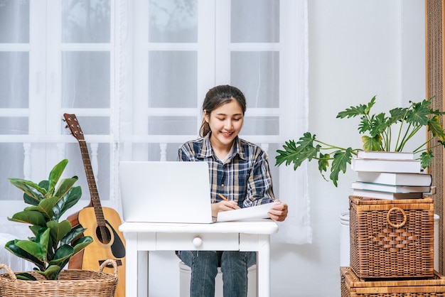 Uma mulher sentada feliz com um laptop na mesa.