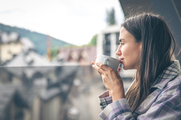 Uma mulher tomando café na varanda pela manhã