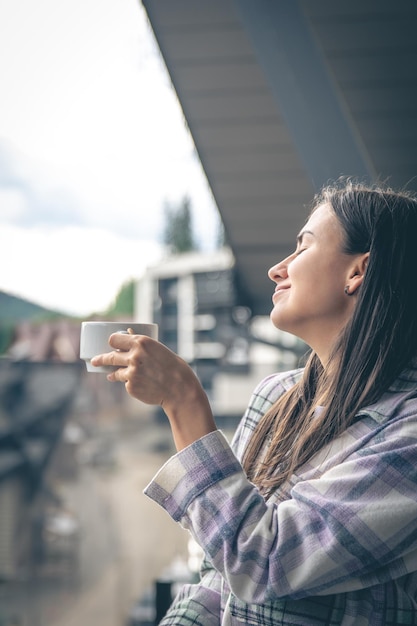 Uma mulher tomando café na varanda pela manhã