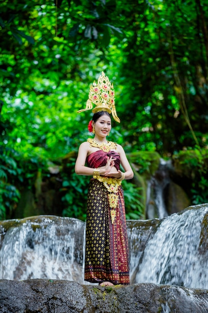 Foto grátis uma mulher vestiu-se com um vestido tailandês antigo na cachoeira.