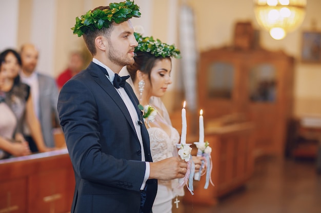 Uma noiva jovem e bonita está de pé com o marido em uma igreja