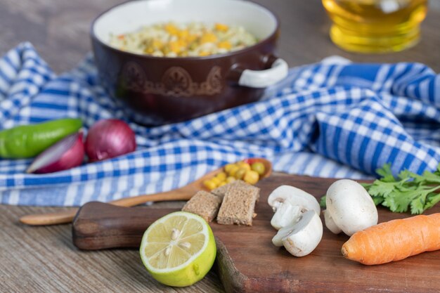 Uma panela de macarrão com legumes e uma colher na toalha de mesa