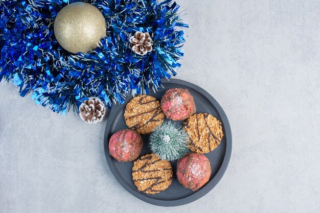 Uma pequena bandeja de biscoitos ao lado de um pacote de decorações de Natal em uma superfície de mármore