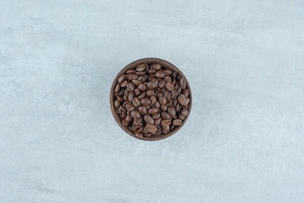 Uma pequena tigela de madeira com grãos de café em branco