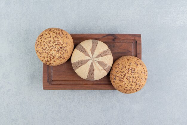 Uma placa de madeira cheia de biscoitos doces.