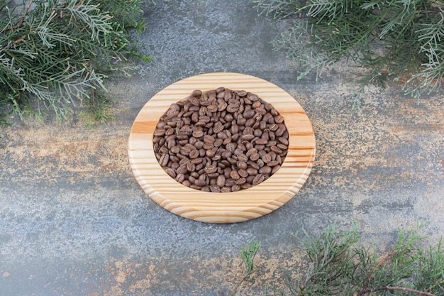 Foto grátis uma placa de madeira com grãos de café sobre fundo de mármore. foto de alta qualidade