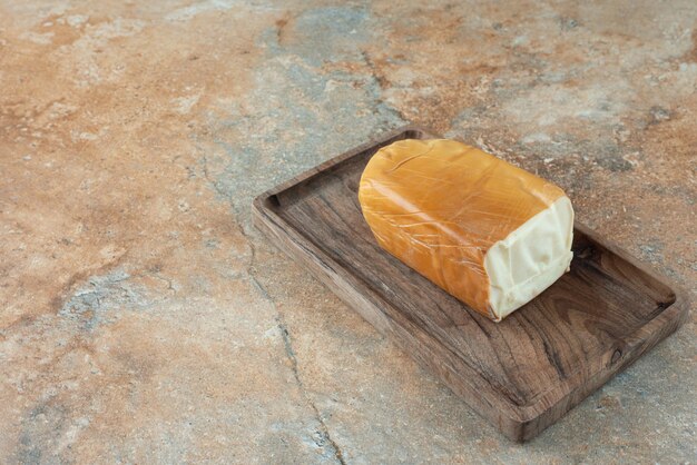 Uma placa de madeira com queijo na mesa de mármore.