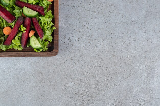 Uma placa de madeira com salada de legumes em uma toalha de mesa. Foto de alta qualidade