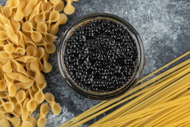Uma placa de vidro de caviar de esturjão preto com macarrão cru.