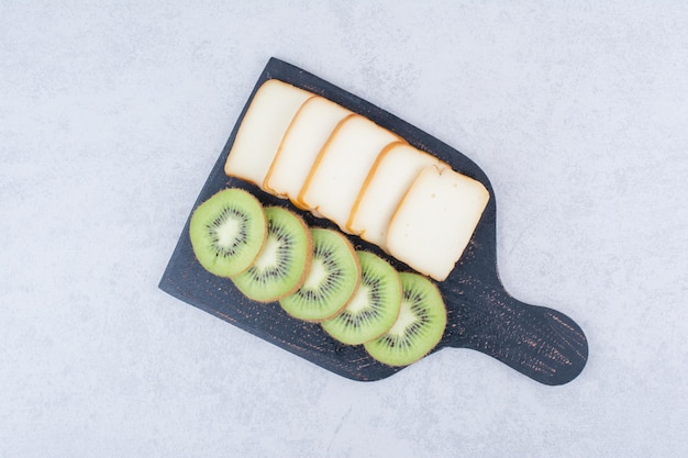 Uma placa escura com pão fatiado e kiwi fresco. foto de alta qualidade