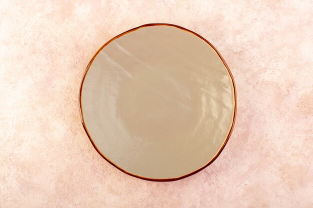 Uma placa redonda marrom de vista de cima em um copo vazio feito de uma cor de mesa de refeição isolada