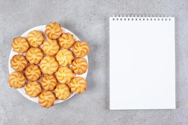 Uma porção completa de biscoitos caseiros ao lado de um bloco de notas no fundo de mármore. foto de alta qualidade