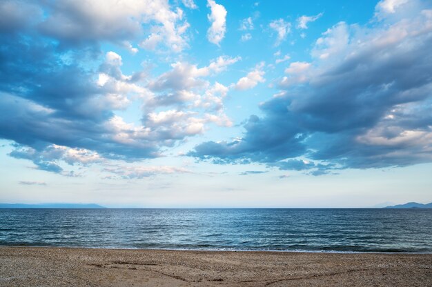 Uma praia e o mar Egeu, céu parcialmente nublado, Grécia