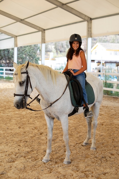 Uma rapariga a aprender a andar a cavalo.