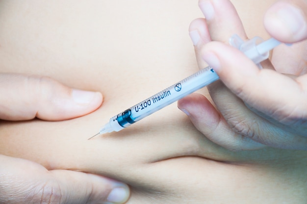 Uma senhora está injetando insulina em seu estômago.