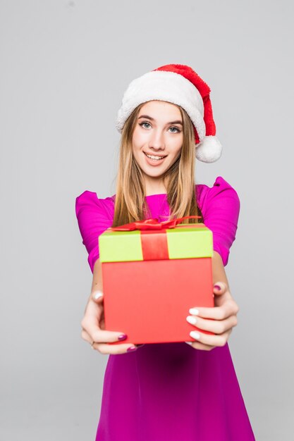 Uma senhora muito sorridente e feliz com um vestido rosa curto e um chapéu de ano novo segurando uma caixa de papel surpresa nas mãos