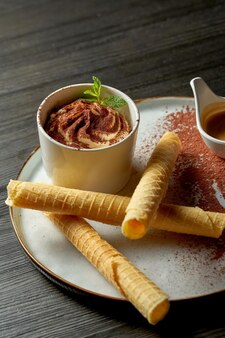 Uma sobremesa italiana apetitosa - tiramisu com uma porção de café expresso. fundo de madeira
