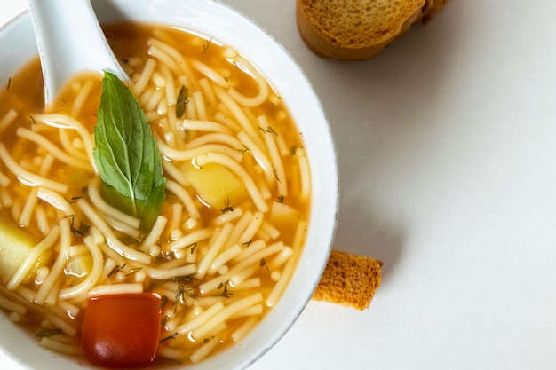 Uma sopa quente de vista de cima com vegetais em pratos brancos e fatias de pão em branco