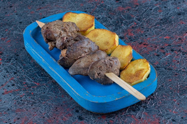 Uma tábua de madeira azul com batata frita com carne