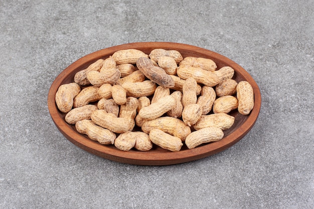 Uma tábua de madeira cheia de amendoins saudáveis com casca