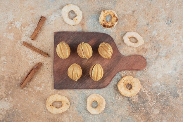 Uma tábua de madeira cheia de biscoitos doces e paus de canela