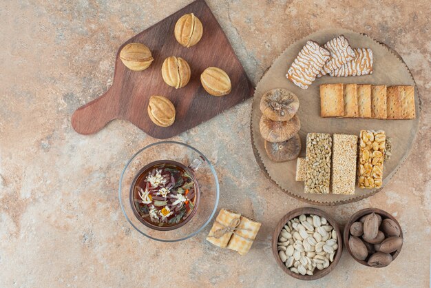 Uma tábua de madeira cheia de biscoitos doces e uma xícara de chá de ervas