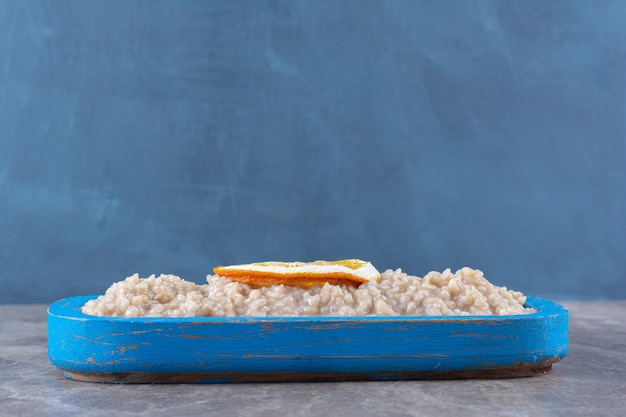 Foto grátis uma tábua de madeira com deliciosa aveia e uma rodela de laranja.