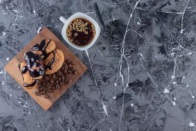 Uma tábua de madeira com minicroissants com chocolate e grãos de café.