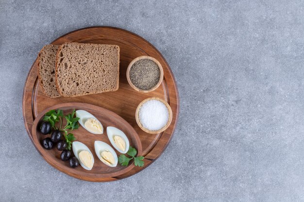 Uma tábua de madeira com ovo cozido e fatias de pão