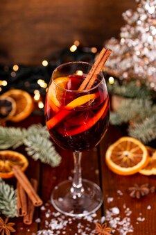 Uma taça de vinho quente na mesa de madeira cercada por decorações de natal bebida festiva de inverno