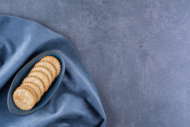 Uma tigela azul de biscoitos de manteiga para chá na toalha de mesa.
