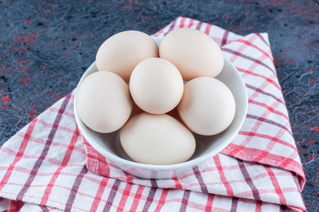Uma tigela branca com ovos de galinha crus