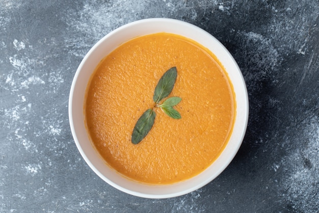 Uma tigela branca de sopa de lentilhas sobre um fundo de mármore.