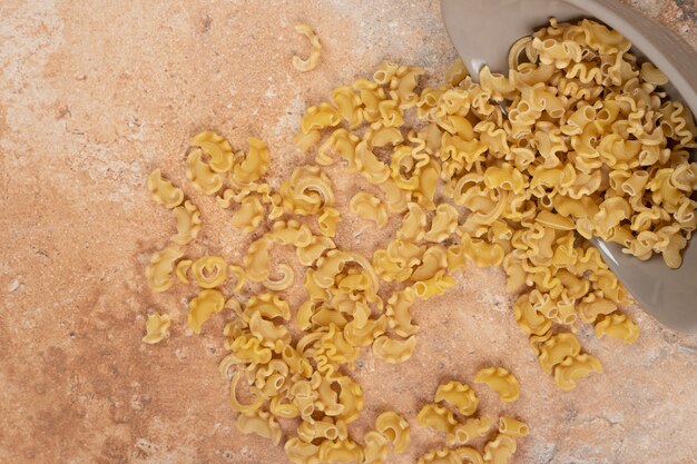 Uma tigela cinza de macarrão não preparado em fundo de mármore. Foto de alta qualidade