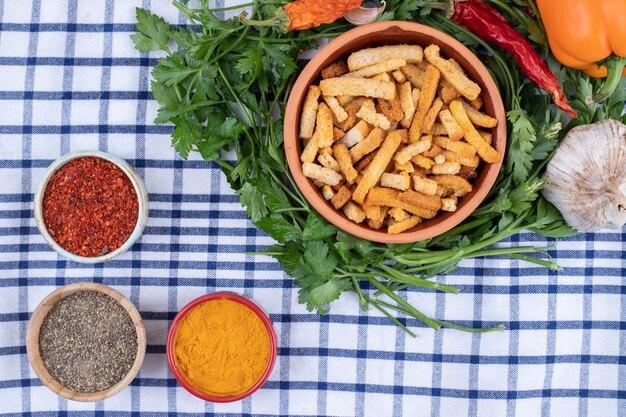 Uma tigela de barro com palitos de pão com vegetais em uma toalha de mesa