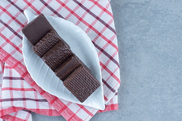 Uma tigela de chocolate coberto com uma barra de wafer crocante na toalha, na mesa de mármore.