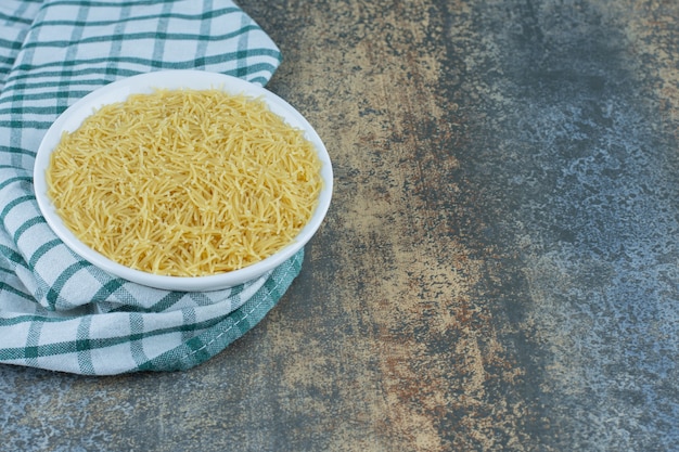 Uma tigela de macarrão na toalha, na superfície do mármore.