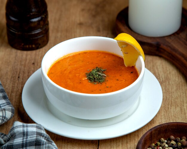 Uma tigela de sopa de lentilha, guarnecida com uma fatia de limão