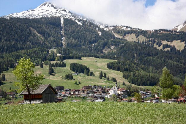 Uma vila com muitas construções em uma paisagem montanhosa cercada por árvores verdes